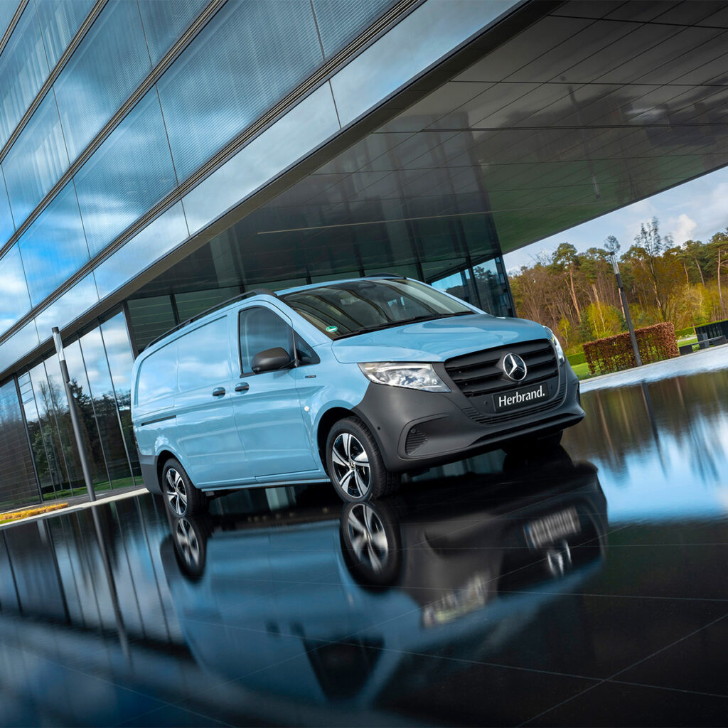 Mercedes-Benz eVito Kastenwagen mit 90 kWh Batterie vor moderner Glasfassade beim Autohaus Herbrand – vollelektrischer Transporter mit bis zu 480 km Reichweite, ideal für gewerblichen Einsatz.