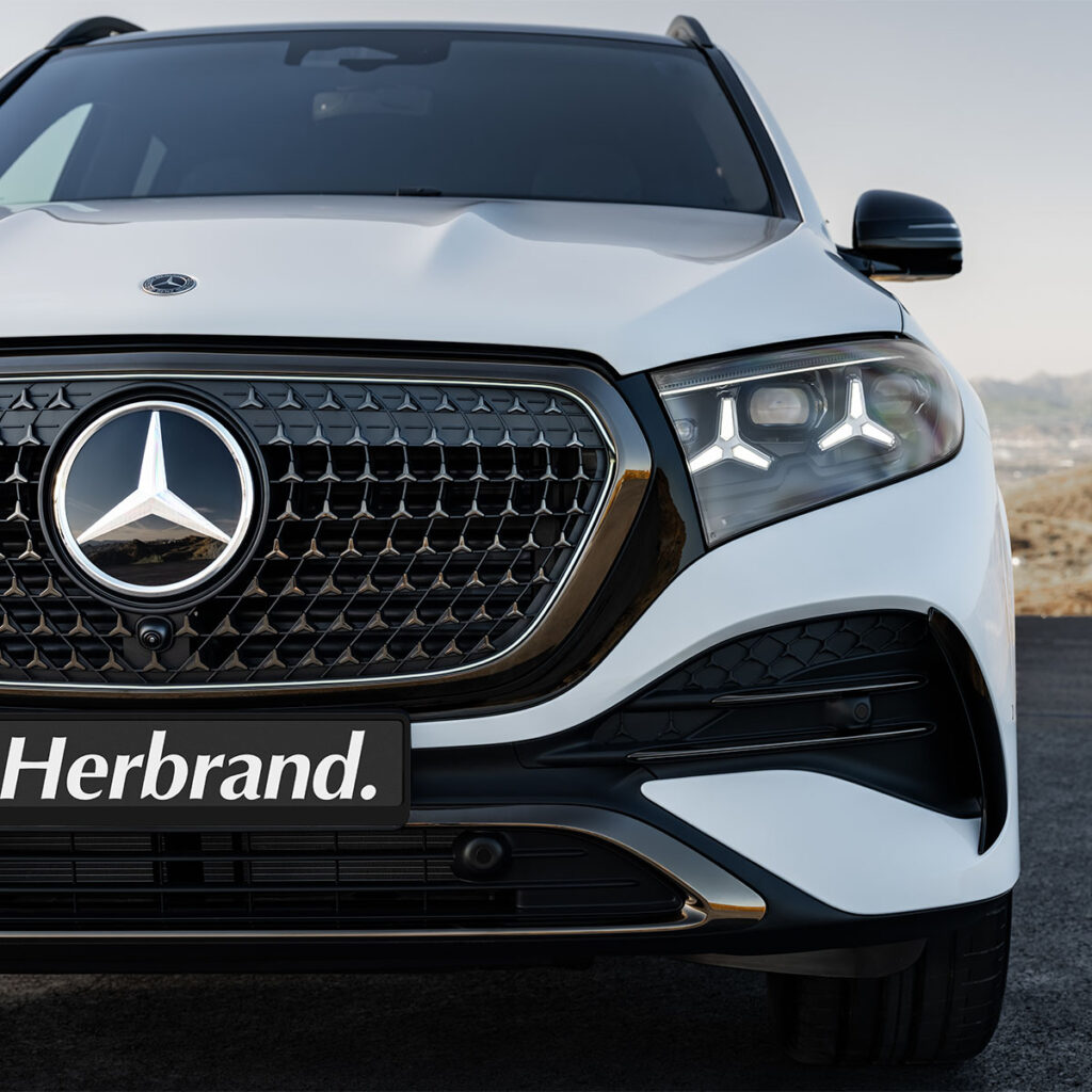 Frontale Nahaufnahme eines weissen Mercedes-Benz-GLE mit Fokus auf Stern und Scheinwerfern mit Herbrand Kennzeichen